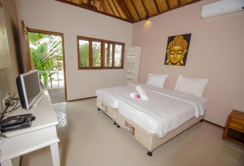 a bedroom with a bed and a desk with a monitor at Si Pitung Village in Gili Air