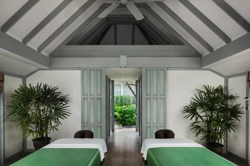 two beds in a room with two plants at The Surin Phuket in Surin Beach