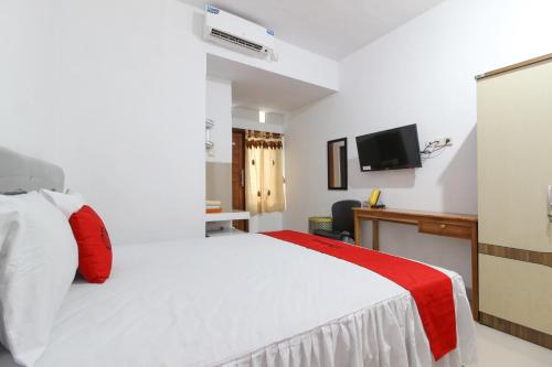 Habitación de hotel con cama blanca y TV en RedDoorz Syariah at Kebun Raya Yogyakarta, en Yogyakarta