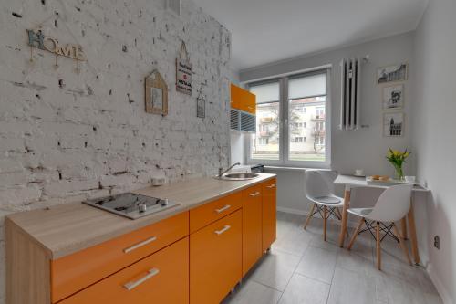 a kitchen with orange cabinets and a white brick wall at Apartamenty Old Town Mniszki in Gdańsk