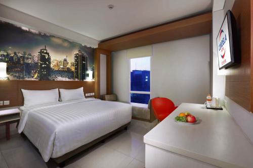 a bedroom with a bed and a desk and a window at Cordela Senen Jakarta in Jakarta