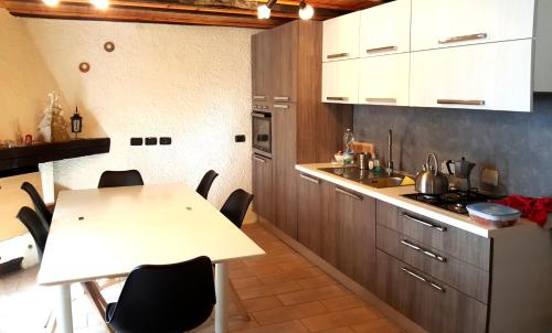 una cocina con armarios blancos y una mesa con sillas. en Casa Ronit, en Delebio