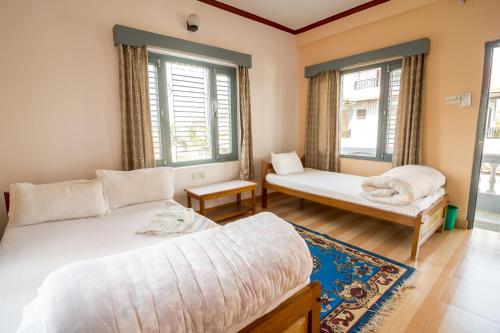 a bedroom with two beds and two windows at Hotel Mountain View - Lakeside Pokhara in Pokhara