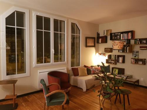 a living room with a couch and two windows at L'EN VERT in Bagnères-de-Bigorre