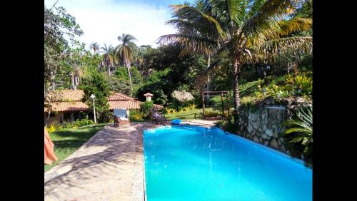 una piscina azul en un patio con palmeras en Pousada Rancho Flores, en Caeté