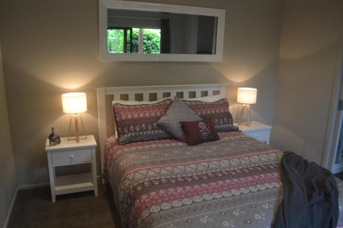 a bedroom with a bed with two night stands and two lamps at Highlands on Homestead in Oamaru