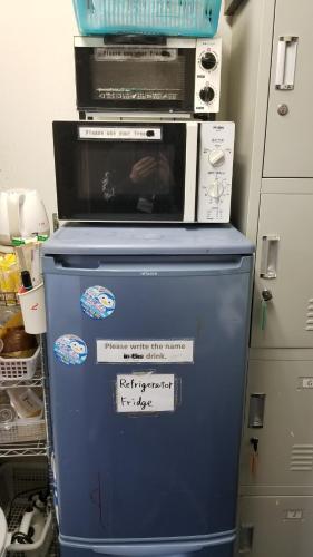 a microwave sitting on top of a blue refrigerator at Kiyamachi Guesthouse in Kyoto