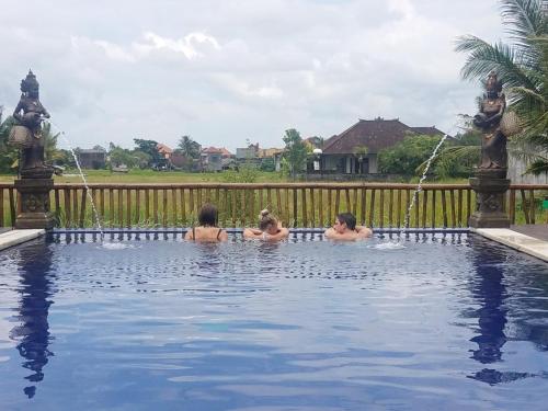 Tres chicas nadando en una piscina con una fuente en Green Paddy Hostel & Villa, en Ubud
