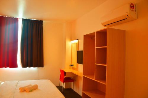 a bedroom with a bed and a desk and a window at Hotel Jeti Tg Gemok in Padang Endau