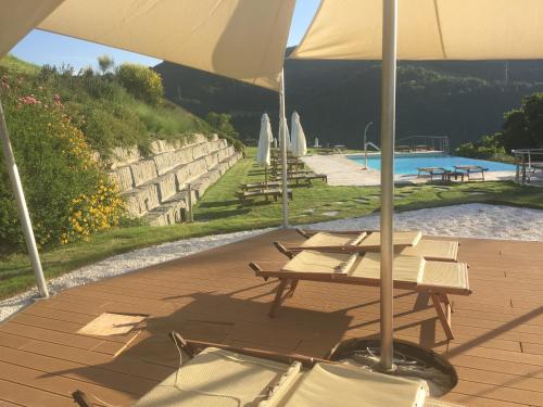 a group of tables and umbrellas next to a pool at Agriturismo Corte Dei Mori in Brisighella