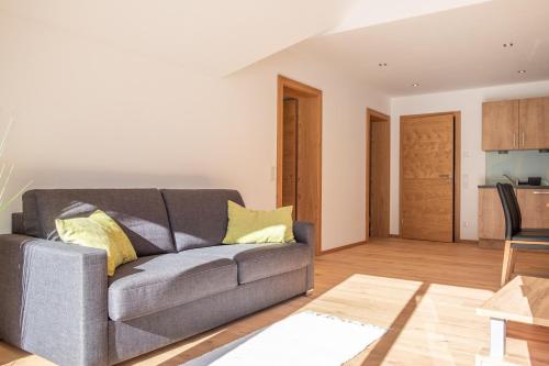 a living room with a gray couch and a kitchen at Landhaus Seereith in Faistenau