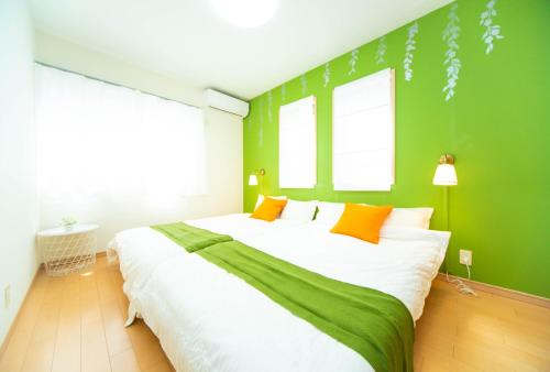 a bedroom with a large bed with green walls at Park side Villa Izumi Komoike in Izumi