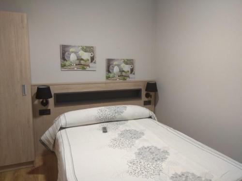 a small bedroom with a bed and two pictures on the wall at Pensión A Carballeira in Villalba