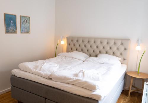 Una cama con sábanas blancas y almohadas en un dormitorio en Mortens Kro Boutique Hotel en Aalborg