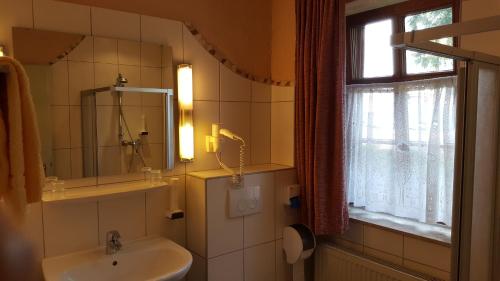 a bathroom with a sink and a mirror and a window at Hotel Goldflair am Rathaus in Korbach