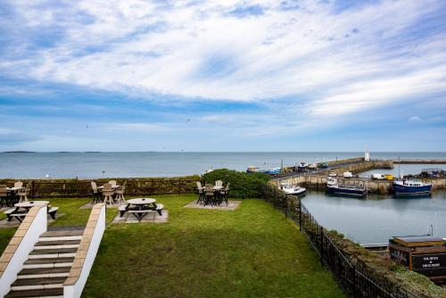 a patio with a view of the water and a dock at The Bamburgh Castle Inn - The Inn Collection Group in Seahouses