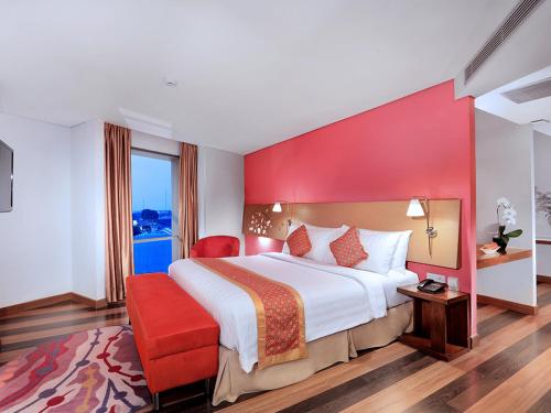 Cette chambre comprend un grand lit et un mur rouge. dans l'établissement ASTON Palembang Hotel & Conference Centre, à Palembang