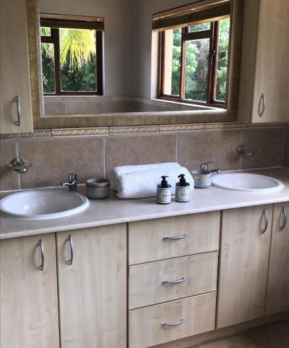 a bathroom with two sinks and a mirror at Goedehoop Boutique Manor House in Malelane