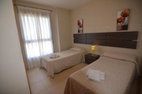 a hotel room with two beds and a window at Apartamentos Entremares - Grupo Antonio Perles in Calpe