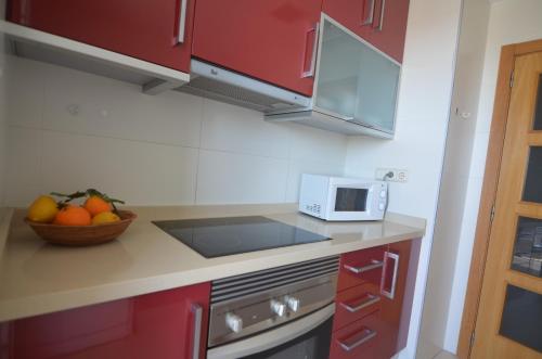 a kitchen with red cabinets and a bowl of fruit at Apartamentos Entremares - Grupo Antonio Perles in Calpe