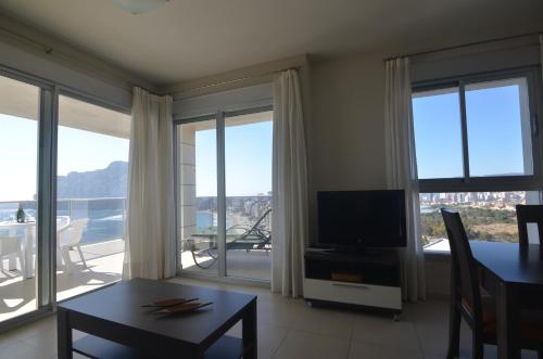 a living room with a television and a table with a tableablish at Apartamentos Entremares - Grupo Antonio Perles in Calpe