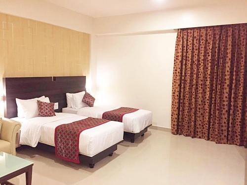 a hotel room with two beds and a window at Sai International Hotel in Dāvangere