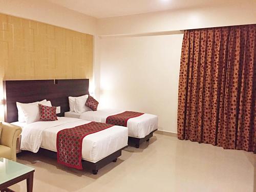 a hotel room with two beds and a window at Sai International Hotel in Dāvangere