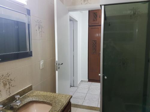 ein Bad mit einem Waschbecken und einer Glastür in der Unterkunft PITANGUEIRAS BEACH in Guarujá