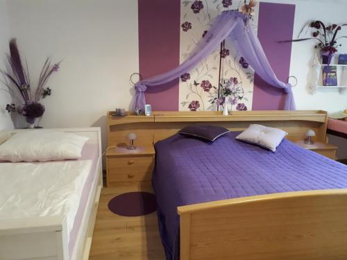 - une chambre avec un lit violet à baldaquin dans l'établissement Serpina, à Löbsal