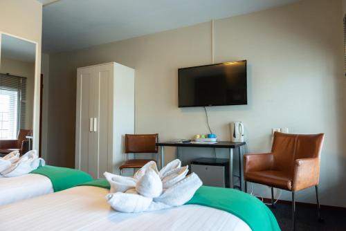 a hotel room with two beds and a flat screen tv at Hotel en Grand Café De Pauw in Roermond