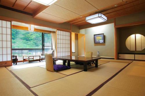 een kamer met een tafel en stoelen en een groot raam bij Enraku in Kurobe