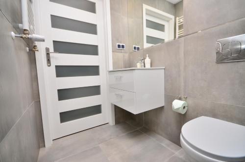 a bathroom with a toilet and a sink and a mirror at APARTAMENT - PORTA MARE - LEŚNE TARASY - 45B/2 in Dziwnówek