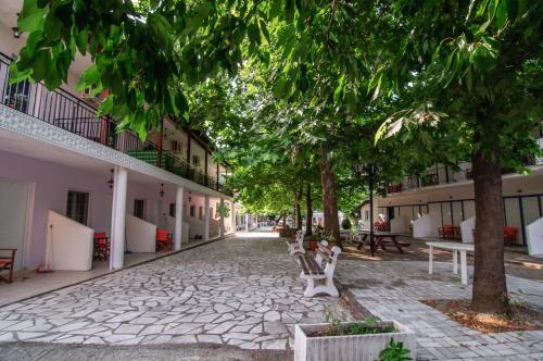 a cobblestone street with benches and trees and buildings at Musses in Kókkinon Nerón