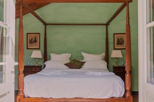 a bedroom with a canopy bed with white sheets and pillows at Chez Jules et Léonie in Valmondois