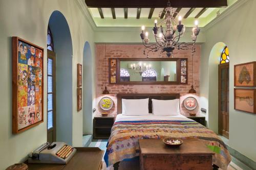 a bedroom with a bed and a chandelier at Calcutta Bungalow in Kolkata