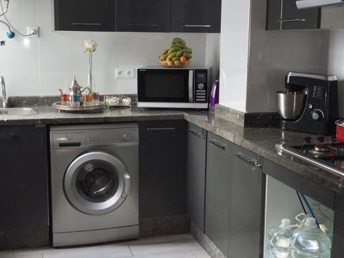 una cucina con lavatrice e microonde di Appart Hotel Monaco a Tangeri