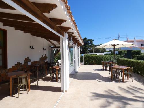 a patio area with chairs, tables and umbrellas at Hostal Port Fornells in Fornells