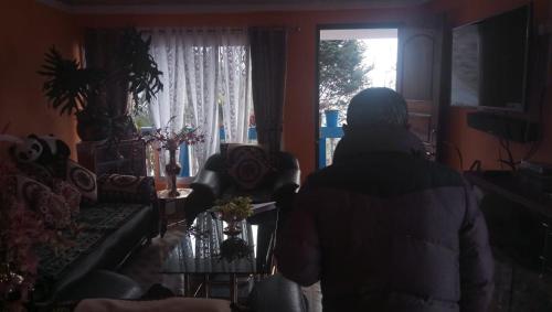 a person standing in a living room looking out a window at Vamoose Sanjeema Tea Estate Homestay in Kurseong