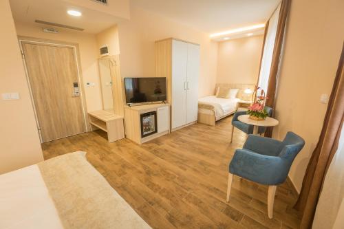 a living room with a television and a chair and a couch at Hotel Mar Garni in Belgrade