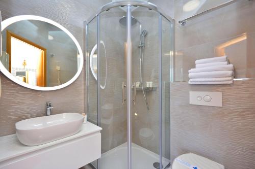 a bathroom with a shower and a sink and a mirror at Hotel Adriana in Split