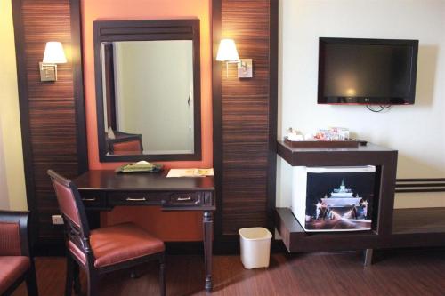 a hotel room with a desk and a mirror and a television at Charoen Thani Hotel, Khon Kaen in Khon Kaen