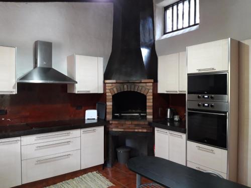 a kitchen with white cabinets and a brick fireplace at Monte frio de Tenerife in La Guancha
