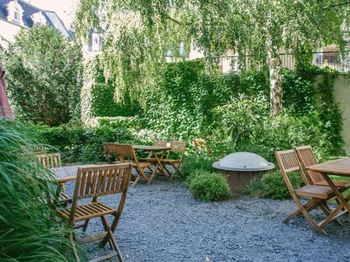 um jardim com cadeiras de madeira, uma mesa e bancos em Adveniat Paris em Paris