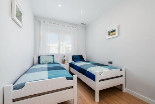 2 camas en un dormitorio con paredes blancas y suelo de madera en PENTHOUSE CABO ROIG - ALDEAS I, en Orihuela Costa