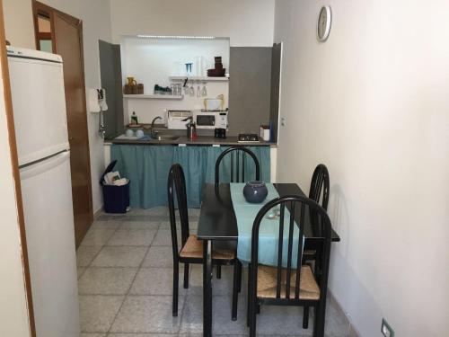 eine Küche mit einem Tisch und Stühlen sowie einem Kühlschrank in der Unterkunft San Vito Lo Capo Via Savoia 250 Casa vacanze in San Vito lo Capo
