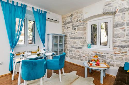 a dining room with blue chairs and a stone wall at La Rocca Apartment Old Town Kotor in Kotor