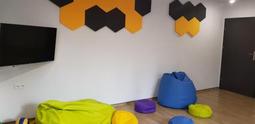 a room with a flat screen tv and colorful chairs at Dom Goscinny Skarpa in Krynica Zdrój