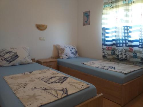 two twin beds in a room with a window at Holiday S&M in Lopar