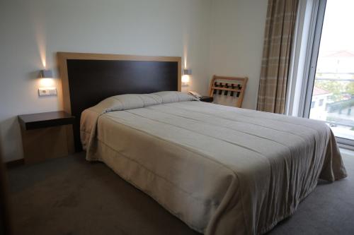 a bedroom with a large bed with a large window at Hotel Recinto in Fátima