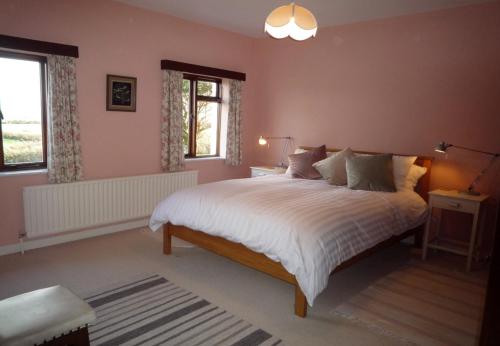 een slaapkamer met een groot bed met witte lakens bij Dingle Bay View in Dingle